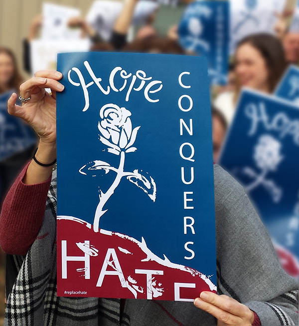 people holding hope conquers hate posters